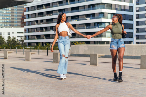 young girls strolling by the city holding hands
