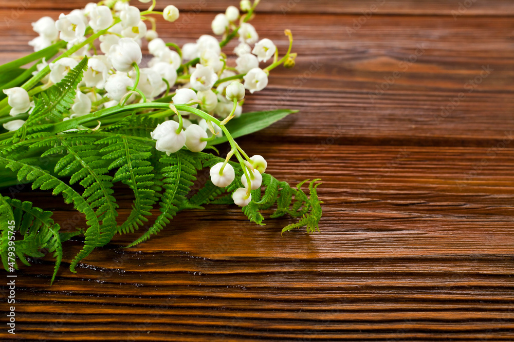 Bunch of natural green fern leaves with lily of the valley or may bells flowers on a wooden background. Copy space. Bunch of natural green fern leaves with lily of the valley or may bells flowers on a wooden background. Copy space.