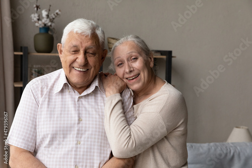 Portrait of happy bonding affectionate old senior 70s married man and woman posing at home, looking at camera showing sincere loving feelings, retired mature family couple strong relations concept. © fizkes
