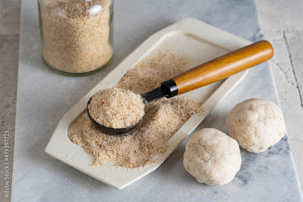 Psyllium husk on spoon soluble fiber supplement and raw bread or buns balls made of it before