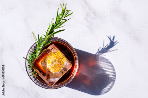 Fényképezés alcoholic cocktail negroni with a block of ice on a light background with a shad