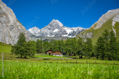 Idyllic mountain meadow and alpine huts in front of the imposing Grossglockner, Tyrol, Austria, Europe photo