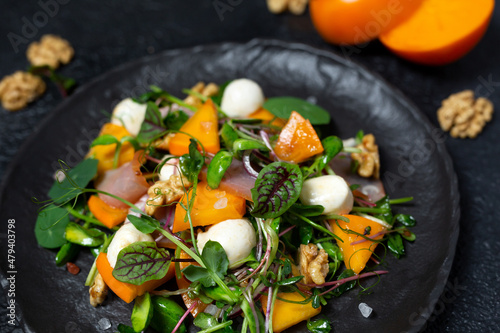 Healthy salad with persimmon, microgreens, nuts and feta cheese. Fitness nutrition