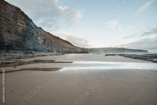 Robin Hood's Bay, Yorkshire, United Kingdom - December 05 2022: Cliff and beach on the east coast of the island at high tide.