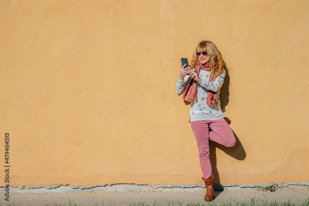 woman with mobile phone isolated on the wall outdoors