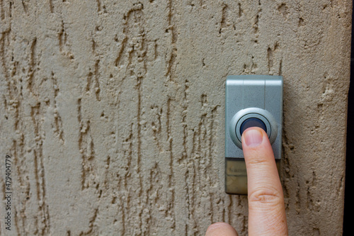 Selective focus on a caucasian finger pressing a  round button on an outdoor doorbell Fototapeta