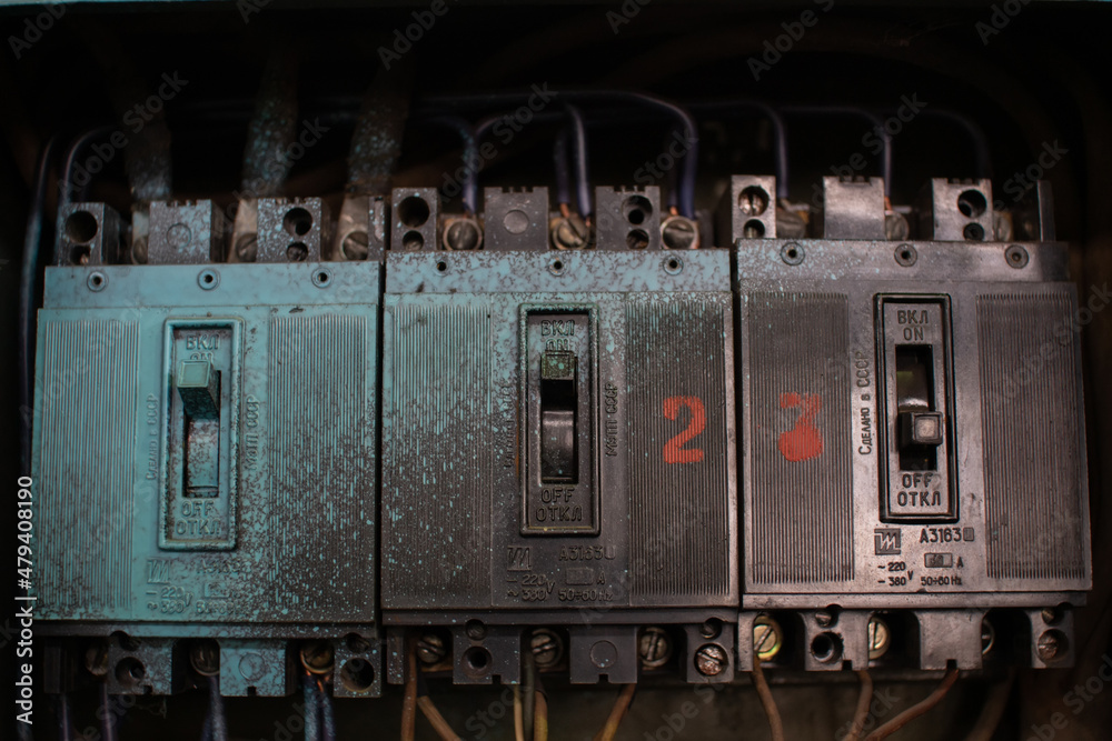Three old Soviet three-phase black circuit breakers in a switchboard.