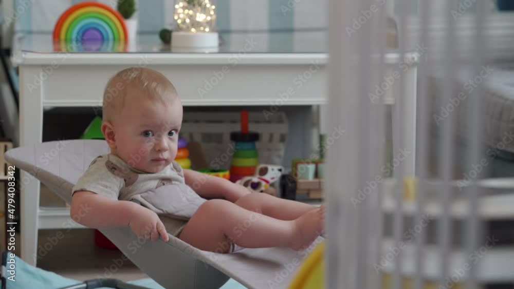 Adorable baby sitting in infant bouncer, 10 month old caucasian kid using legs and arm muscles to spring up and down. High quality 4k footage Adorable baby sitting in infant bouncer, 10 month old caucasian kid using legs and arm muscles to spring up and down. High quality 4k footage