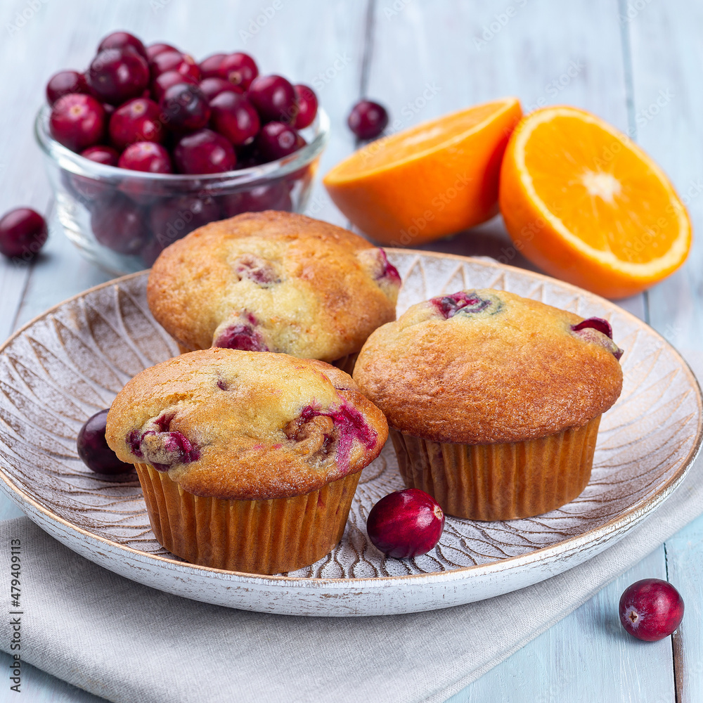 Cranberry orange muffins on wooden plate, square format Cranberry orange muffins on wooden plate, square format