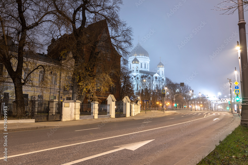 The road in the center of the city at night without traffic. Temple against the background of the night sky. Night in the city center. Backlit architecture