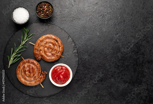 grilled sausages in the form of a spiral on skewers on a stone background  with copy space for your text