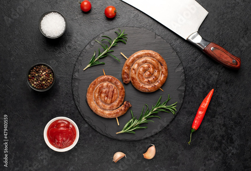 grilled sausages in the form of a spiral on skewers on a stone background