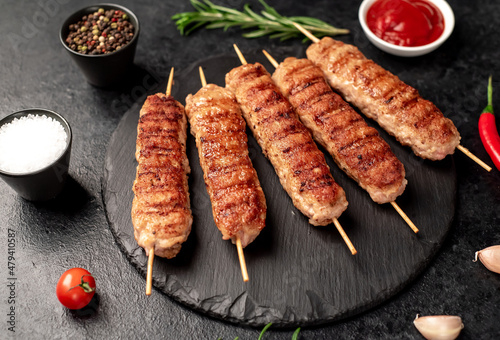 grilled lula kebab on skewers with spices on a stone background