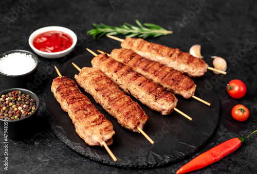 grilled lula kebab on skewers with spices on a stone background