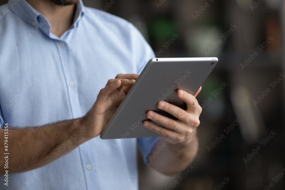 Crop close up Caucasian young man holding using modern tablet, typing on screen, writing message chatting in social network, businessman freelancer working online, browsing electronic device apps Crop close up Caucasian young man holding using modern tablet, typing on screen, writing message chatting in social network, businessman freelancer working online, browsing electronic device apps