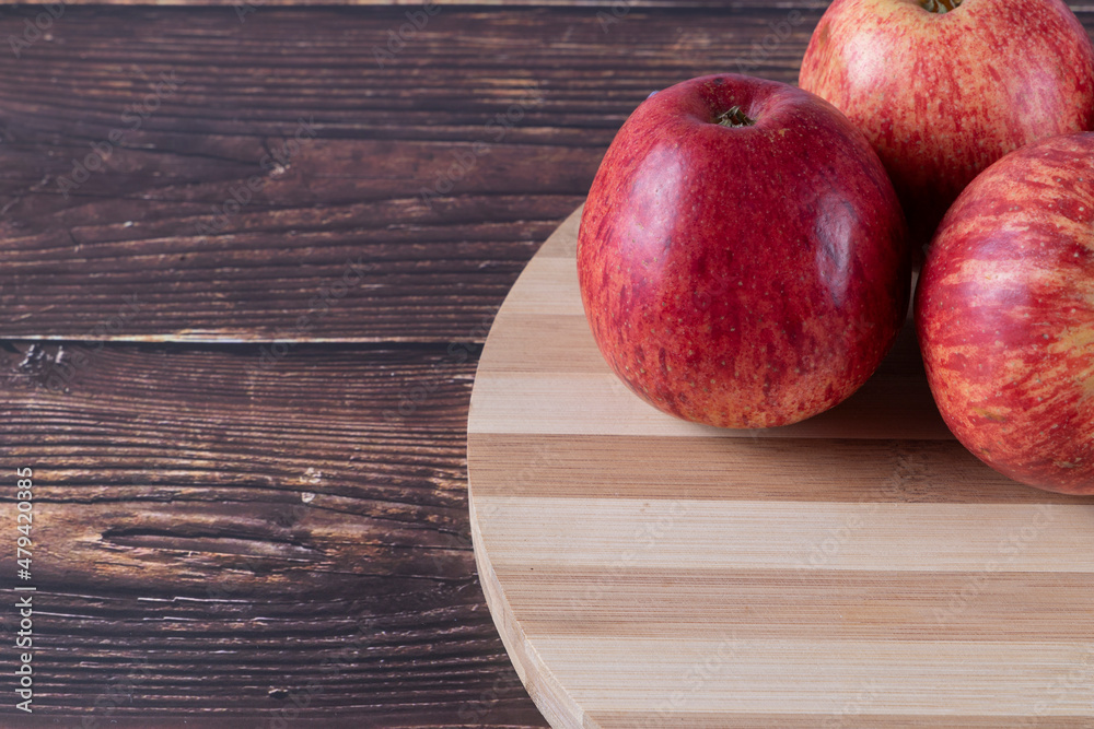 Tasty apples (Malus domestica, scientific name in Latin) on a bamboo board, table in rustic wood. Selective focus. Tasty apples (Malus domestica, scientific name in Latin) on a bamboo board, table in rustic wood. Selective focus.