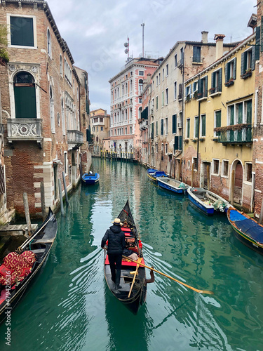 A gondolier travels along a beautiful, azure green canal in Venice surounded by the famous pink, stone buildings. Taken in winter. Venice - Italy © Madeleine Deaton