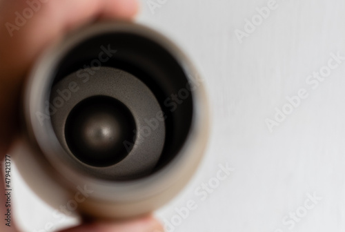 Bottom of metal thermos close-up through its neck on blurred background