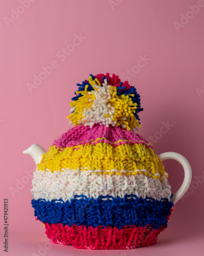 pot of tea with tea cosy on pink background 