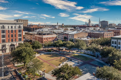 Aerial view of Ellis square Congress street in Savannah historic downtown with oval shaped park, rooftop building, tourists hanging out 