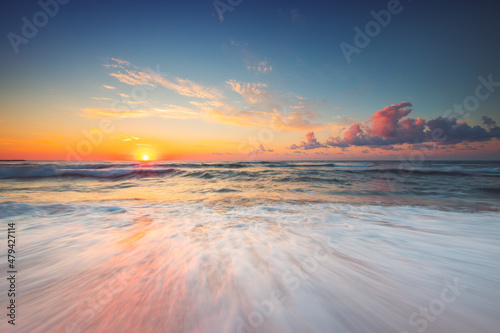Beautiful sunrise over the sea waves and beach sand