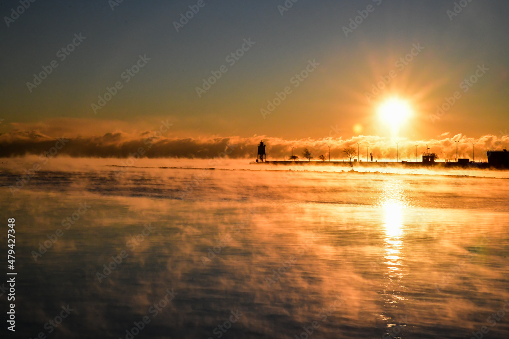 Frozen lake water steam at sunrise in winter 