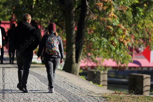 Para młodych ludzie, kobieta i mężczyzna z plecakami spaceruje w parku we Wrocławiu.	