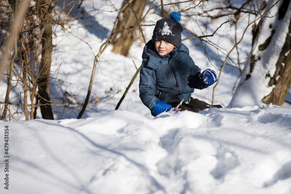 Young boy climbs on the snow-covered hill . Young boy climbs on the snow-covered hill .