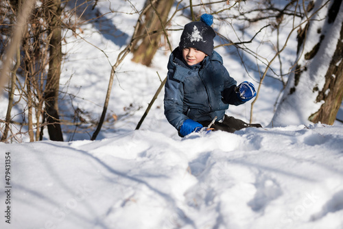 Young boy climbs on  the snow-covered hill .