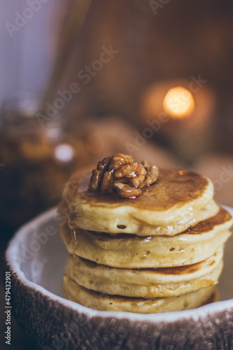 Stack of delicious pancakes with honey, nuts on wooden background