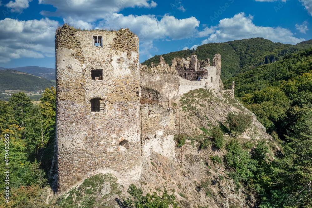 Aerial summer view of Sasov castle in Slovakia above the Hron river with circular donjon tower and partially restored walls on a hilltop
