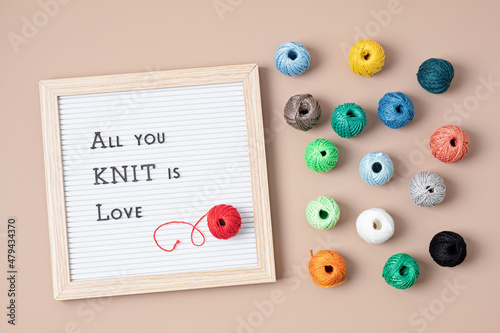 Balls of yarn and letter board with text All you knit is love. Craft hobby background with cotton yarn in brightl colors. Recomforting, destressing hobby photo