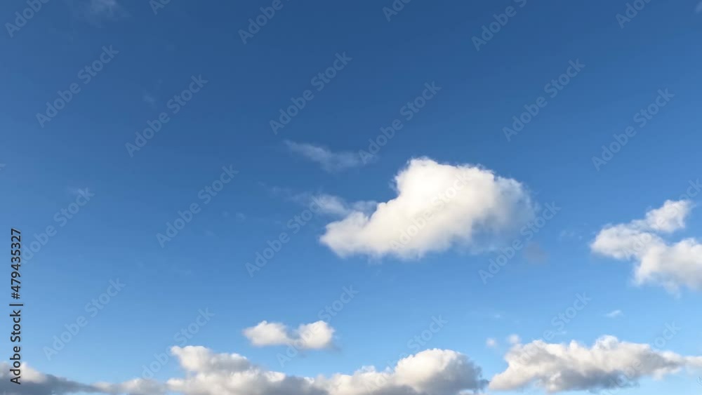 Beautiful clouds float across the sky, a plane flies in the distance.