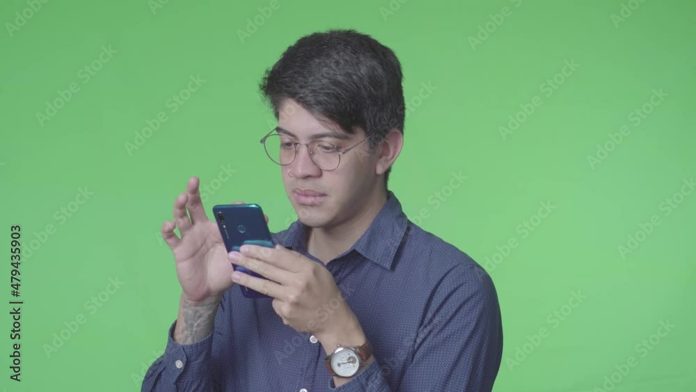 Hombre latino recibiendo llamada telefónica con fondo verde Hombre latino recibiendo llamada telefónica con fondo verde