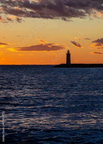 stunning sunset with cloudscape over the sea with a lighthouse in the foreground and clouds on the horizon 