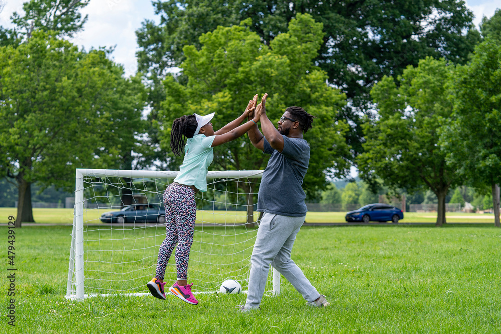 Father and daughter playing soccer in park