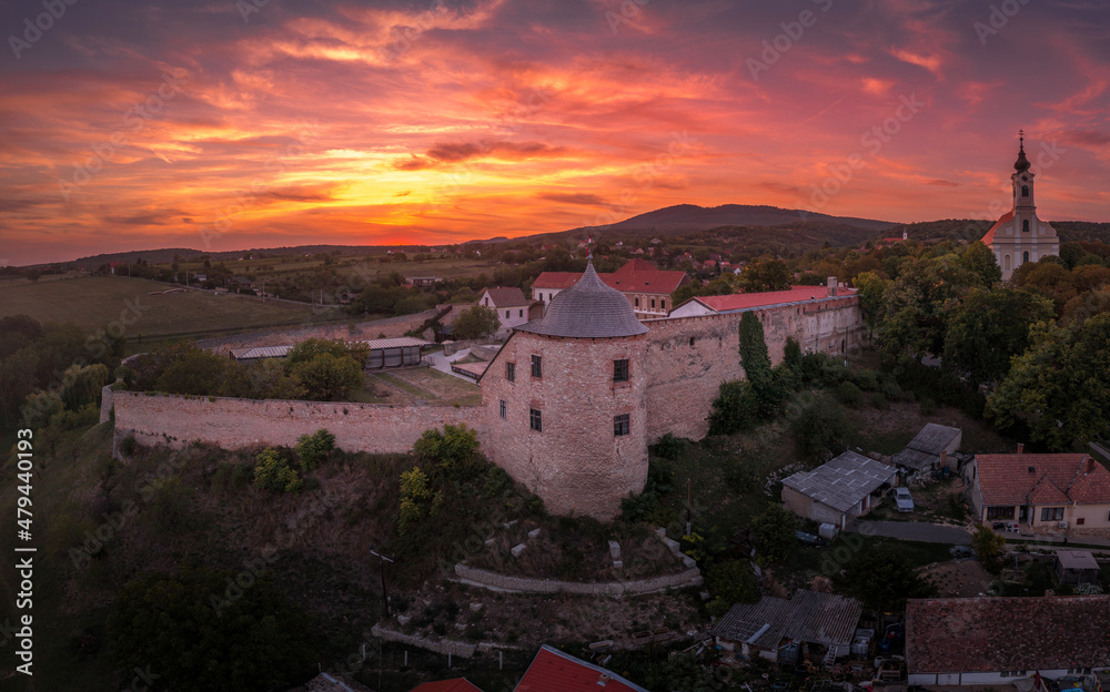 Aerial sunset shot of Pecsvarad fortified church, abbey  and castle with tower, gate on a hilltop in Baranya county Hungary with dramatic colorful sky