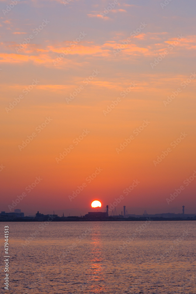 Fototapeta premium 早朝、朝日にキラキラ輝き、黄金色に輝く海。兵庫県芦屋市芦屋浜より大阪湾を臨む。遠くに大阪南港のビルが見える