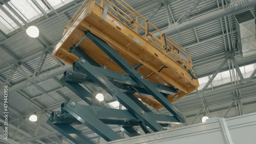 Yellow color new modern telescopic aerial platform lifts workers to work at heights, is presented at the exhibition. Shot in motion