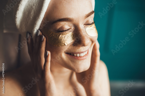 Canvastavla Close-up portrait of a woman with a towel on head taking care of her skin with under eye patches