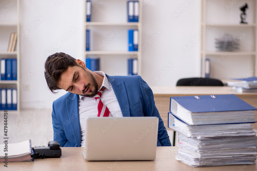 Young male employee and too much work in the office Young male employee and too much work in the office