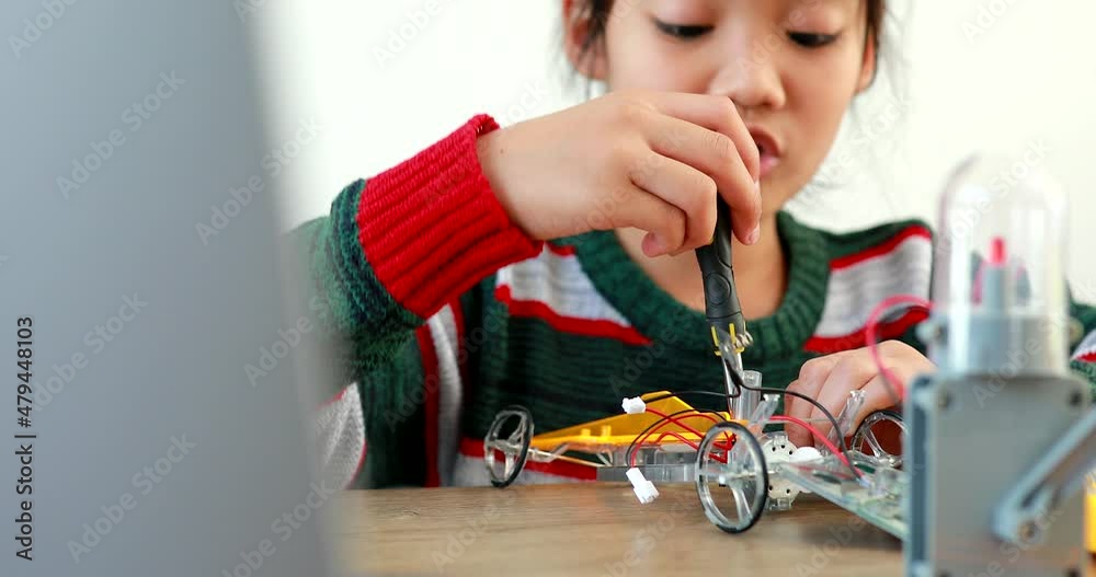 The little girl asian building robotic car in science lesson in the house . Which increases the development and enhances learning skills gifted brilliant children working with technology.