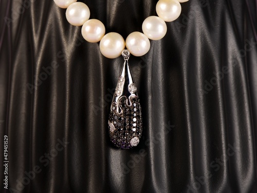 Women's platinum pendant with a black and white diamonds on a preciouse pearlsnecklace photo