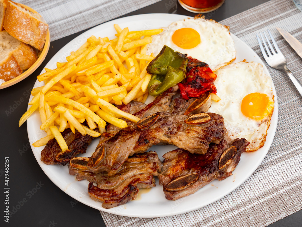 Traditional Galician combo-meal of grilled pork short ribs churrasco with crispy fried potatoes, eggs and baked peppers.