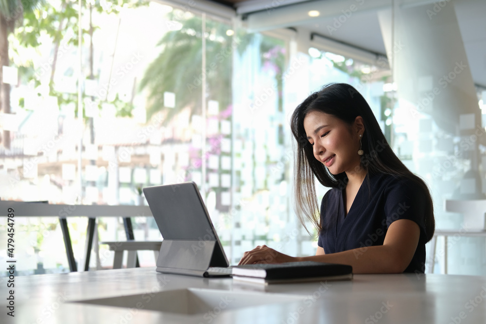 Smiling young businesswoman working with computer tablet in modern workplace. Smiling young businesswoman working with computer tablet in modern workplace.