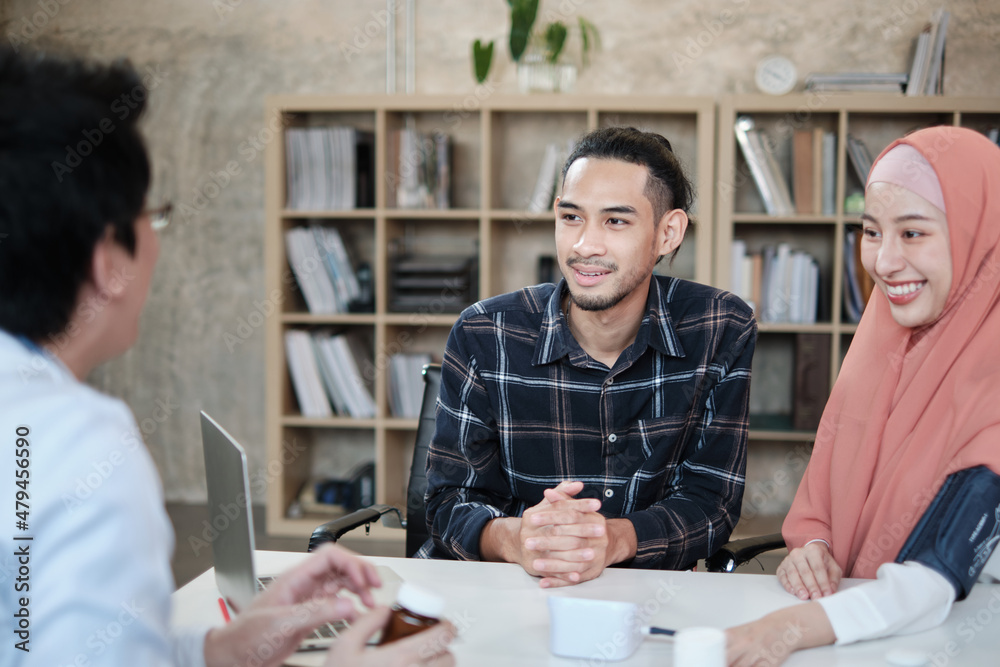 Obraz premium People medical insurance clinic service. Young Muslim couple discussing and consulting with a professional Asian male doctor about his wife's health who is a beautiful woman wears a hijab in office.