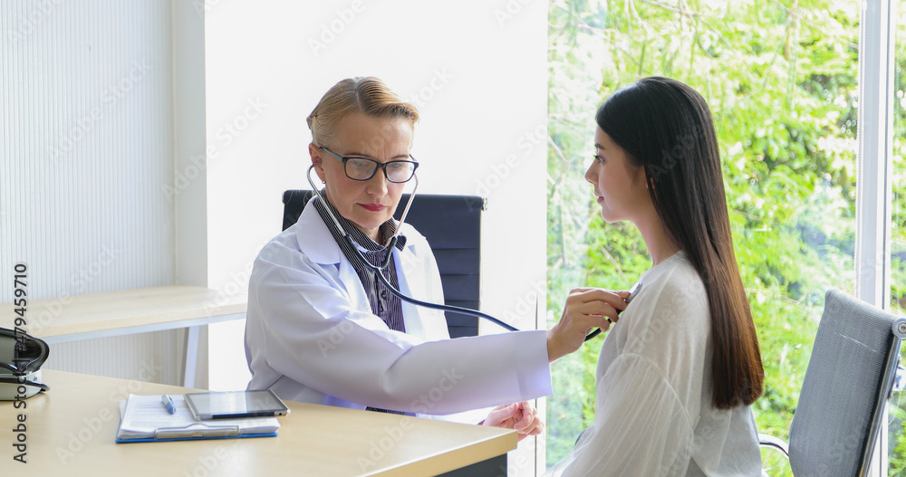 Women doctor used a stethoscope to check the lungs of the woman patient at the hospital.