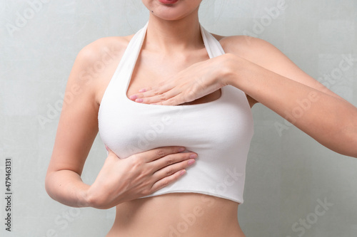 Woman hand checking lumps on her breast cancer for signs of breast cancer on background. Healthcare concept.