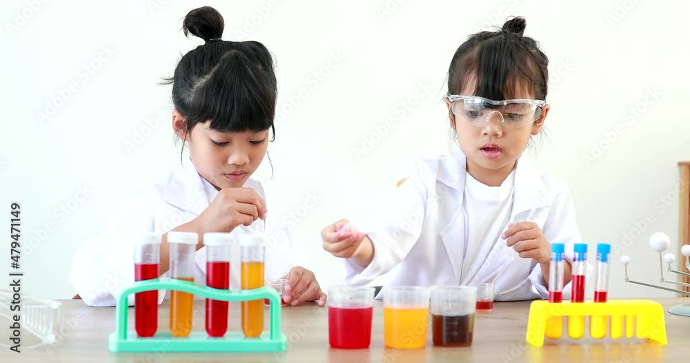 Little girl asian cute little student child learning research and doing a chemical experiment while making analyzing and mixing liquid in test tube at home on the table. Little girl asian cute little student child learning research and doing a chemical experiment while making analyzing and mixing liquid in test tube at home on the table.