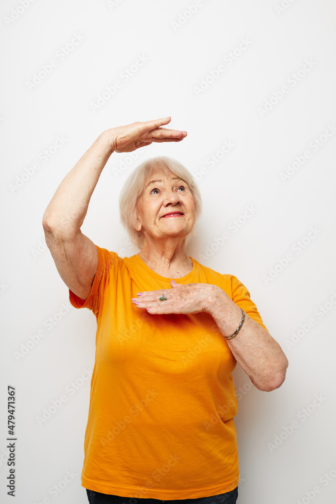 smiling elderly woman in a yellow t-shirt posing light background smiling elderly woman in a yellow t-shirt posing light background